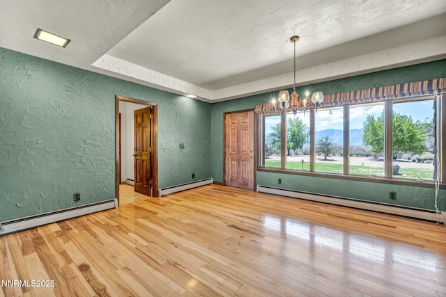 1405 Primrose Ln, Minden, NV 89423 - empty room with baseboard heating, a chandelier, wood-type flooring, a textured wall, and a textured ceiling
