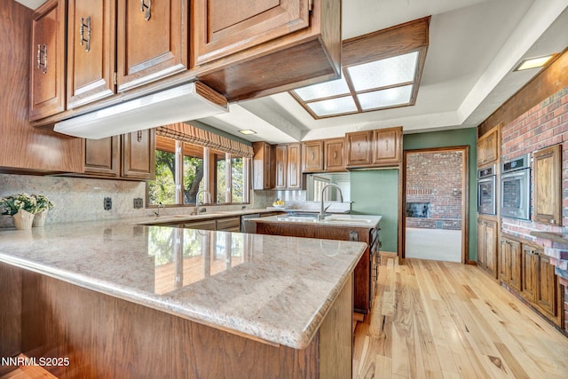 1405 Primrose Ln, Minden, NV 89423 - kitchen with a peninsula, brown cabinets, light stone countertops, backsplash, and light wood-type flooring