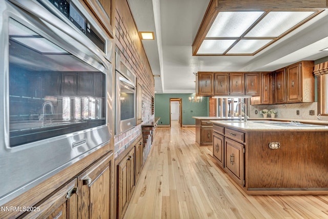 1405 Primrose Ln, Minden, NV 89423 - kitchen with light wood finished floors, brown cabinets, light countertops, a kitchen island with sink, and double oven