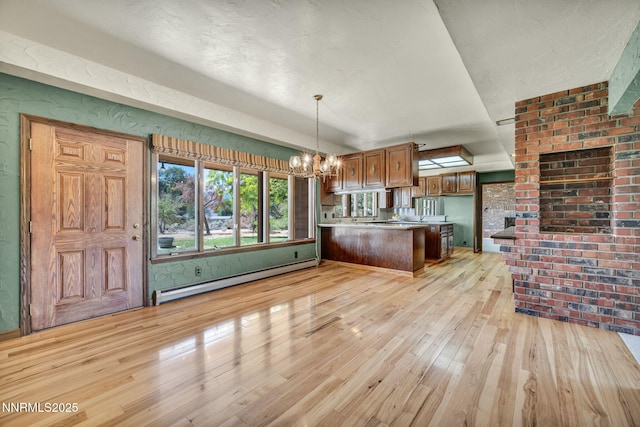 1405 Primrose Ln, Minden, NV 89423 - kitchen with a baseboard radiator, light wood finished floors, a chandelier, brown cabinets, and a peninsula