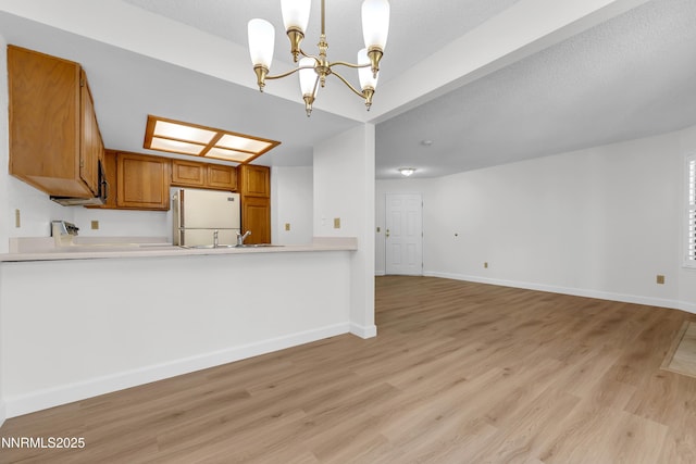 2875 Idlewild Dr Apt 5, Reno, NV 89509 - kitchen with freestanding refrigerator, brown cabinets, a chandelier, light wood finished floors, and light countertops