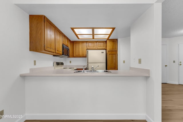 2875 Idlewild Dr Apt 5, Reno, NV 89509 - kitchen featuring black microwave, freestanding refrigerator, stove, and a peninsula