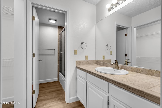 2875 Idlewild Dr Apt 5, Reno, NV 89509 - bathroom with vanity, a walk in closet, wood finished floors, and a textured ceiling