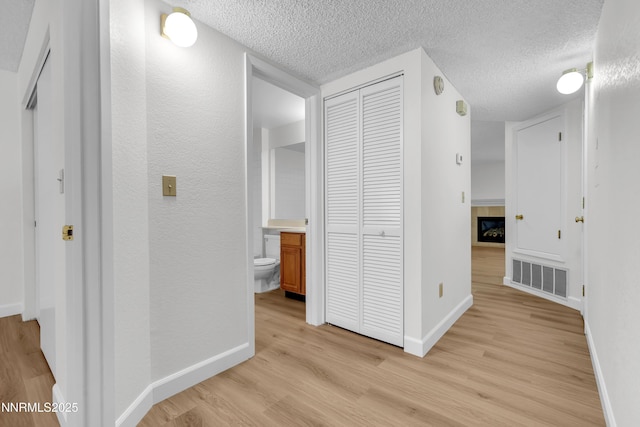 2875 Idlewild Dr Apt 5, Reno, NV 89509 - hallway featuring light wood finished floors, a textured ceiling, and a textured wall