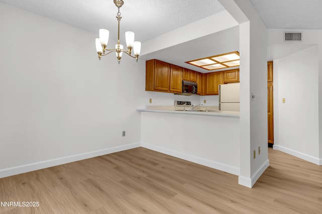 2875 Idlewild Dr Apt 5, Reno, NV 89509 - kitchen with black microwave, freestanding refrigerator, light wood-style flooring, a chandelier, and a textured ceiling