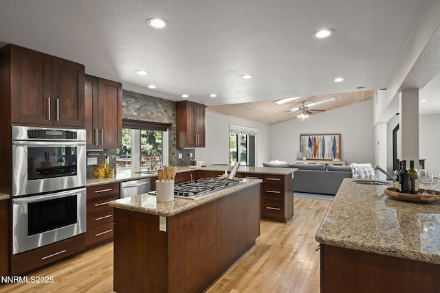 1705 Blue Spruce Rd, Reno, NV 89511 - kitchen featuring appliances with stainless steel finishes, a peninsula, a kitchen island, open floor plan, and light wood-style flooring