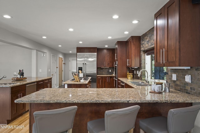 1705 Blue Spruce Rd, Reno, NV 89511 - kitchen with built in refrigerator, a center island, a peninsula, light stone countertops, and tasteful backsplash