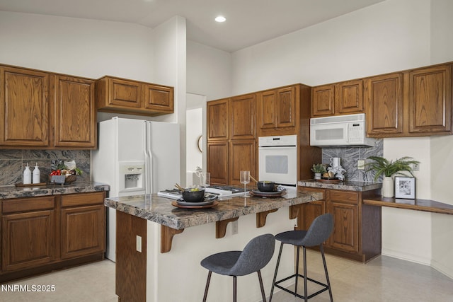 4811 Elkcreek Trl, Reno, NV 89519 - kitchen with white appliances, backsplash, dark countertops, a kitchen breakfast bar, and a center island
