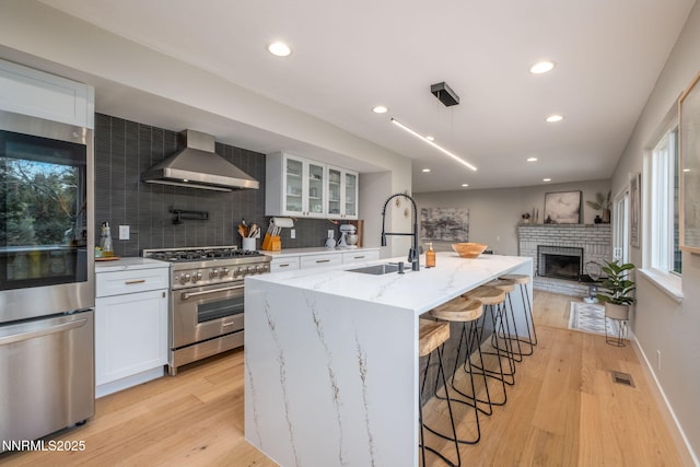 3390 Thornhill Dr, Reno, NV 89509 - kitchen with appliances with stainless steel finishes, wall chimney exhaust hood, decorative backsplash, light stone countertops, and recessed lighting
