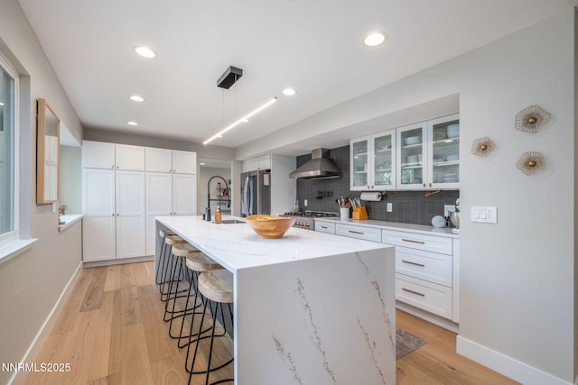 3390 Thornhill Dr, Reno, NV 89509 - kitchen with wall chimney exhaust hood, freestanding refrigerator, a kitchen breakfast bar, range, and light wood finished floors