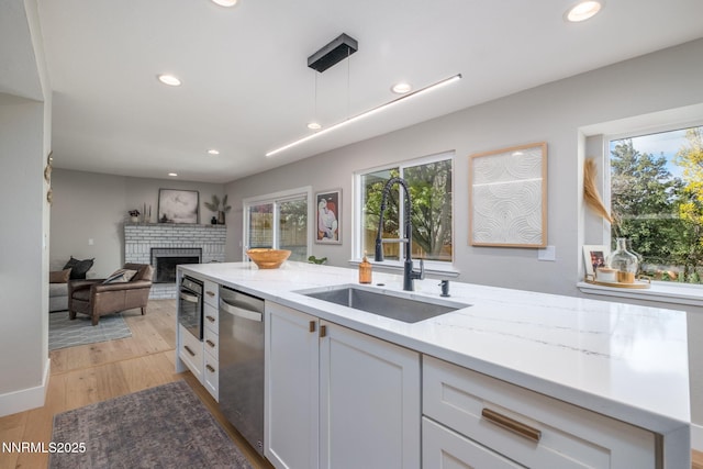 3390 Thornhill Dr, Reno, NV 89509 - kitchen featuring dishwasher, a brick fireplace, recessed lighting, light stone countertops, and white cabinetry