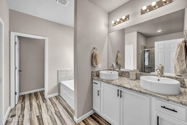 776 Great Basin Ln, Fallon, NV 89406 - bathroom with double vanity, a shower stall, a garden tub, and wood finished floors