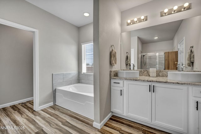 776 Great Basin Ln, Fallon, NV 89406 - bathroom featuring double vanity, a stall shower, a bath, and wood finished floors