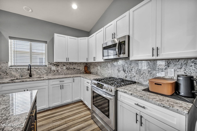 776 Great Basin Ln, Fallon, NV 89406 - kitchen featuring appliances with stainless steel finishes, lofted ceiling, backsplash, white cabinetry, and light stone countertops