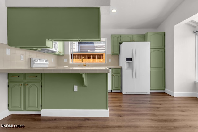 2240 Silver Ridge Dr, Reno, NV 89509 - kitchen with white refrigerator with ice dispenser, green cabinetry, tile countertops, recessed lighting, and wood finished floors