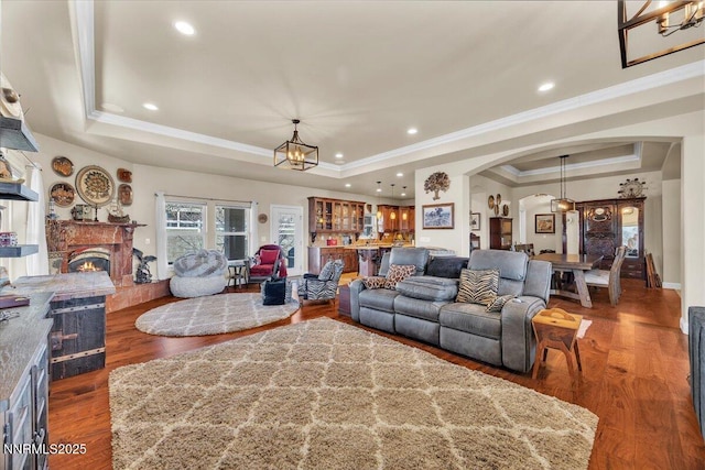 1962 Comstock Dr, Gardnerville, NV 89410 - living room featuring a raised ceiling, arched walkways, crown molding, a lit fireplace, and a chandelier
