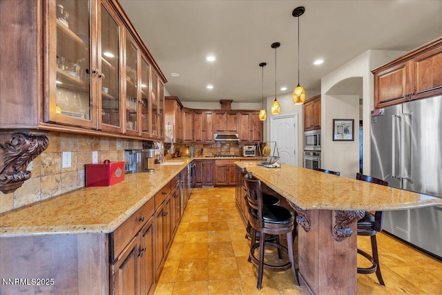 1962 Comstock Dr, Gardnerville, NV 89410 - kitchen featuring stainless steel appliances, a breakfast bar area, backsplash, light stone counters, and a center island with sink