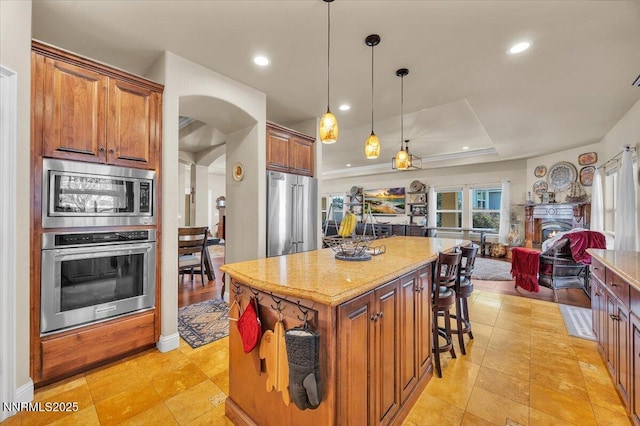 1962 Comstock Dr, Gardnerville, NV 89410 - kitchen featuring stainless steel appliances, light stone counters, a center island, arched walkways, and open floor plan