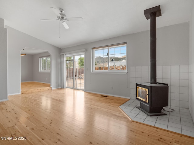 2843 Wade St, Minden, NV 89423 - unfurnished living room featuring wood finished floors, a wood stove, a ceiling fan, lofted ceiling, and arched walkways