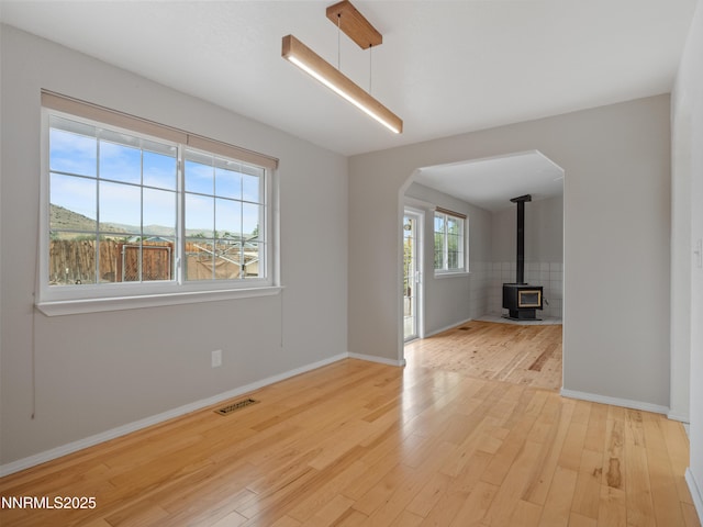 2843 Wade St, Minden, NV 89423 - unfurnished living room with arched walkways, a wood stove, and light wood-style flooring