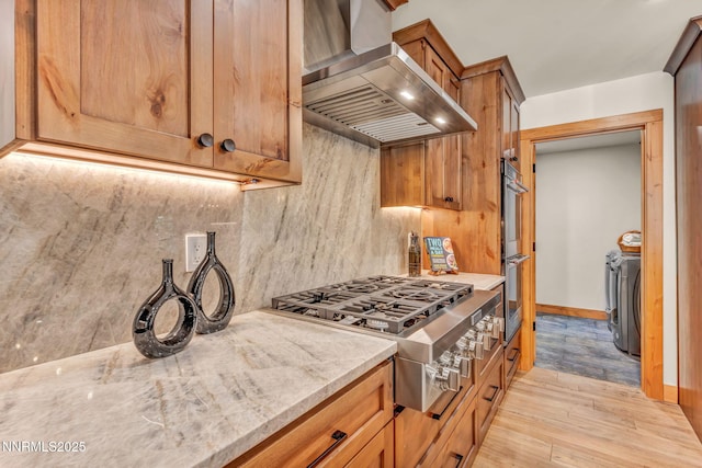 116 Cypress Way, Stateline, NV 89449 - kitchen featuring wall chimney exhaust hood, appliances with stainless steel finishes, decorative backsplash, light wood finished floors, and light stone countertops