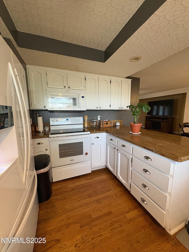 5045 Offenhauser Dr, Winnemucca, NV 89445 - kitchen featuring white appliances, a peninsula, white cabinetry, dark wood-style flooring, and an ornate ceiling