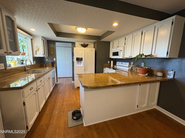 5045 Offenhauser Dr, Winnemucca, NV 89445 - kitchen with white appliances, a peninsula, white cabinets, and dark wood-style flooring