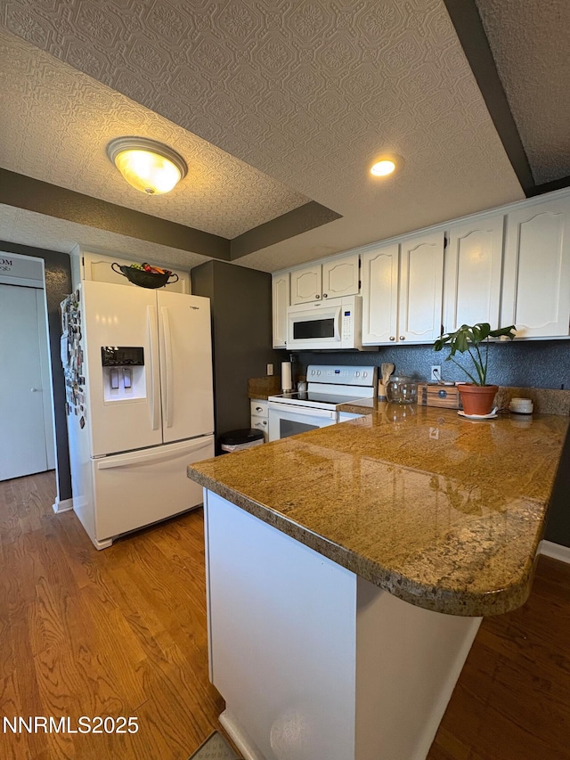 5045 Offenhauser Dr, Winnemucca, NV 89445 - kitchen featuring white appliances, a peninsula, white cabinetry, light wood finished floors, and recessed lighting
