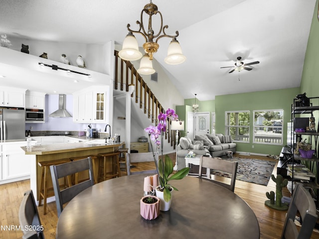 1755 Mizpah St, Winnemucca, NV 89445 - dining room featuring lofted ceiling, stairs, ceiling fan, light wood-style flooring, and a chandelier