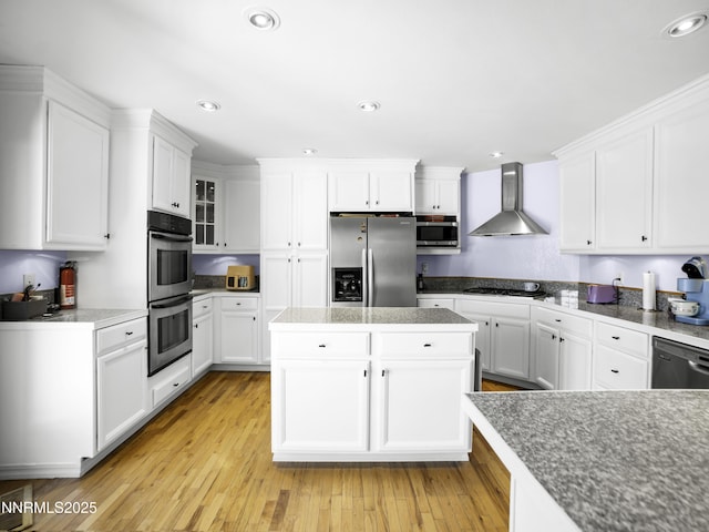 1755 Mizpah St, Winnemucca, NV 89445 - kitchen featuring stainless steel appliances, wall chimney range hood, white cabinetry, light wood-type flooring, and recessed lighting
