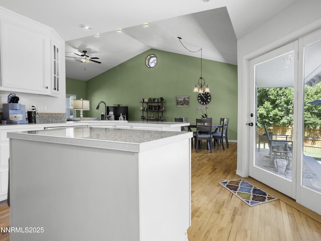 1755 Mizpah St, Winnemucca, NV 89445 - kitchen with a kitchen island, light countertops, light wood-style floors, white cabinets, and lofted ceiling