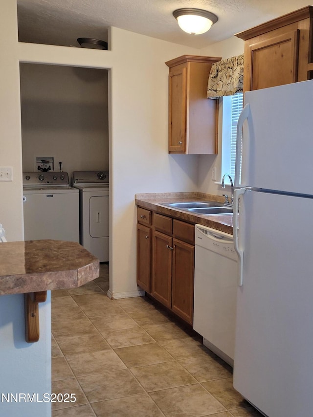 3340 Moon Ln, Winnemucca, NV 89445 - kitchen featuring washing machine and dryer, white appliances, brown cabinets, light tile patterned floors, and dark countertops