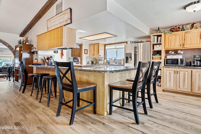 202 Summit Ave, Winnemucca, NV 89445 - kitchen with light brown cabinetry, a peninsula, appliances with stainless steel finishes, a textured ceiling, and light wood finished floors
