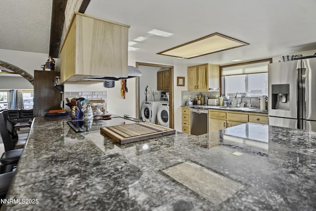 202 Summit Ave, Winnemucca, NV 89445 - kitchen featuring appliances with stainless steel finishes, tasteful backsplash, independent washer and dryer, dark stone counters, and light brown cabinetry
