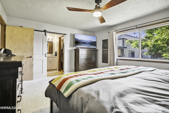 202 Summit Ave, Winnemucca, NV 89445 - bedroom with a barn door, a textured ceiling, ceiling fan, and connected bathroom