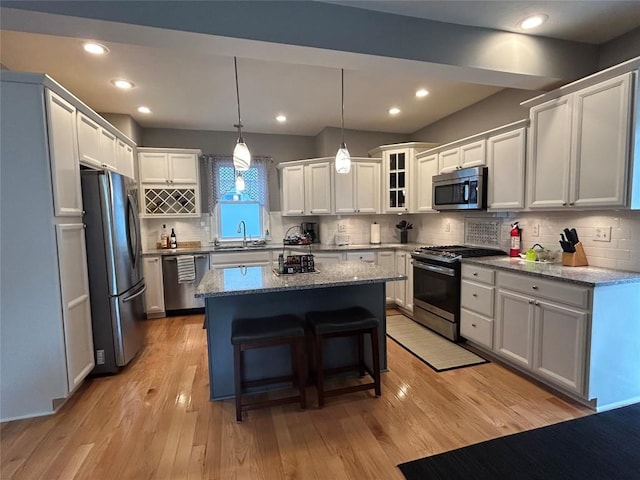 563 W 9th St, Erie, PA 16502 - kitchen with appliances with stainless steel finishes, a center island, light stone counters, light wood finished floors, and recessed lighting