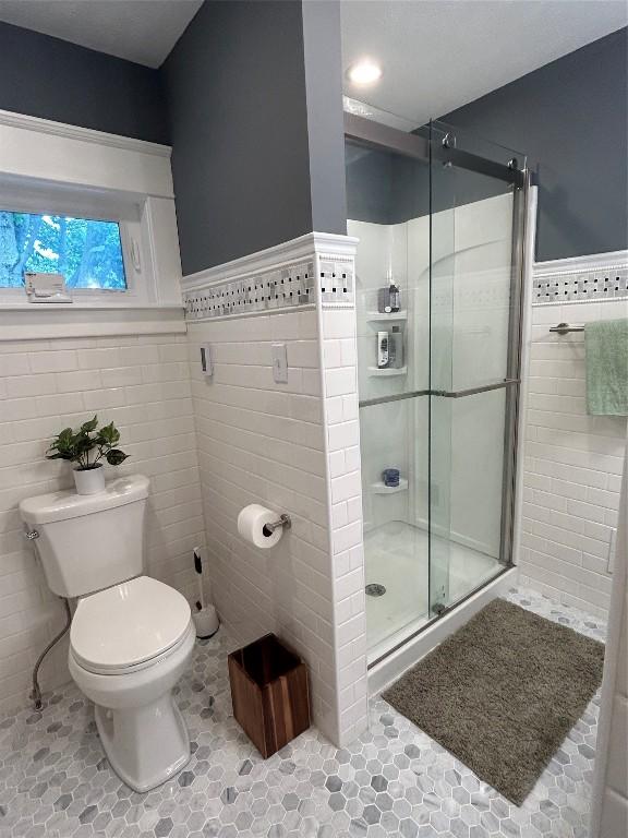 563 W 9th St, Erie, PA 16502 - full bath with tile walls, a shower stall, a wainscoted wall, and tile patterned floors