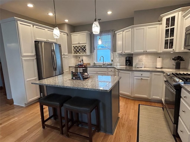 563 W 9th St, Erie, PA 16502 - kitchen with stainless steel appliances, a breakfast bar area, backsplash, light wood-style flooring, and recessed lighting