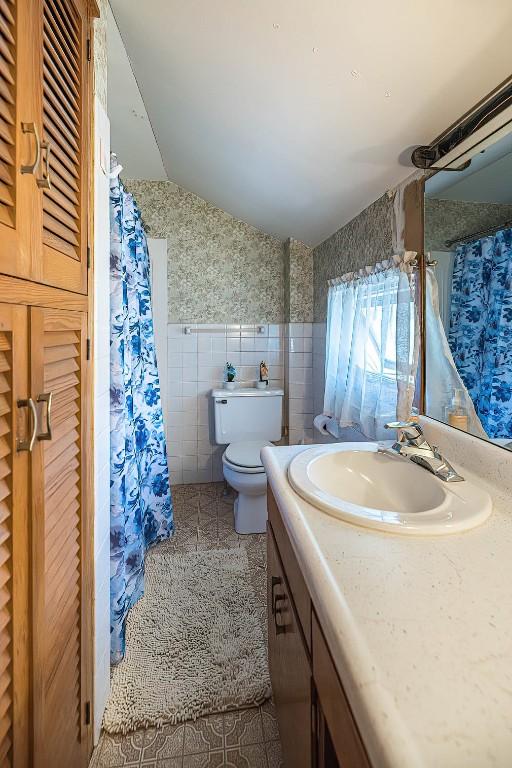 9 E Division St, North East, PA 16428 - bathroom featuring tile walls, vanity, lofted ceiling, curtained shower, and a closet