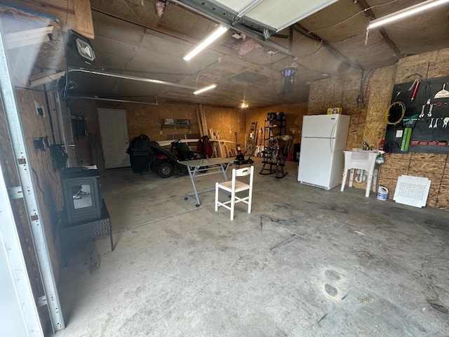 6028 Davidson Rd, Jamestown, PA 16134 - garage with freestanding refrigerator, a wood stove, a workshop area, and a sink