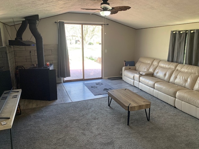 6028 Davidson Rd, Jamestown, PA 16134 - living area featuring a ceiling fan, a wood stove, a textured ceiling, lofted ceiling, and carpet flooring