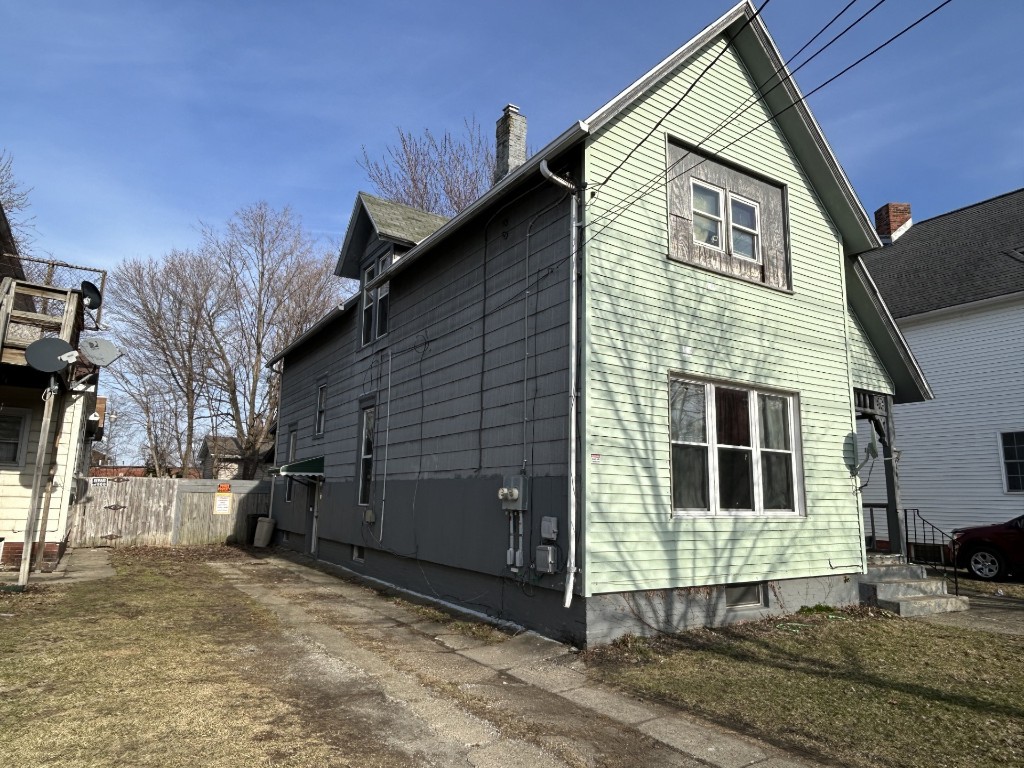 view of side of home with a chimney and fence