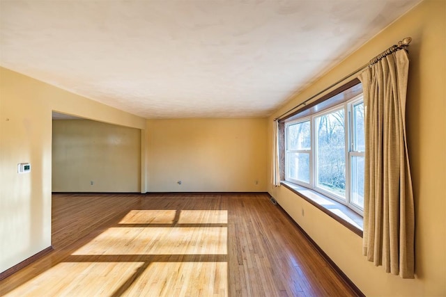 unfurnished room featuring baseboards and wood-type flooring