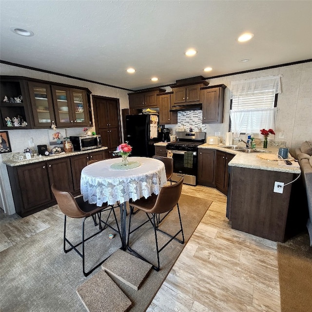 kitchen featuring appliances with stainless steel finishes, dark brown cabinets, crown molding, and sink