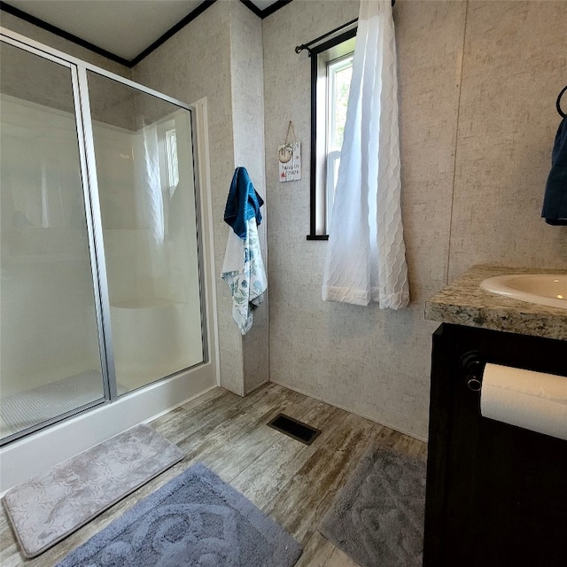 bathroom featuring hardwood / wood-style floors, vanity, and a shower with door