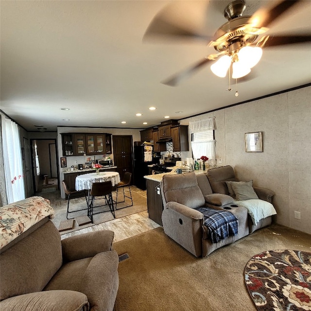 living room featuring light carpet, ceiling fan, and ornamental molding