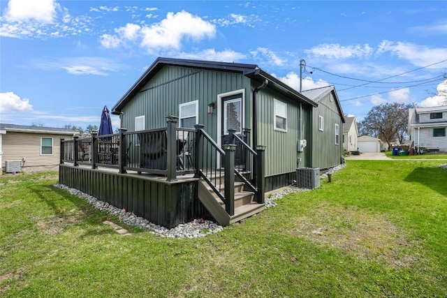 back of property with board and batten siding, central AC unit, a deck, and a lawn