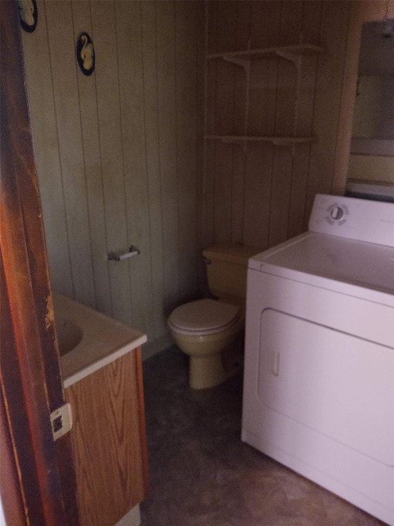 bathroom featuring vanity, toilet, washer / dryer, and wooden walls