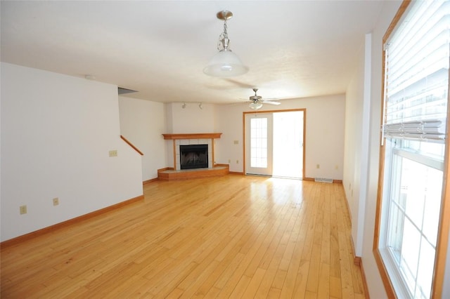 unfurnished living room featuring ceiling fan, a fireplace, and light wood-type flooring