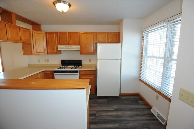 kitchen featuring dark wood-type flooring, white appliances, and kitchen peninsula